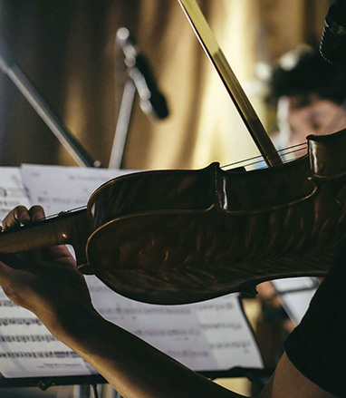 A violinist holding their instrument while looking at sheet music